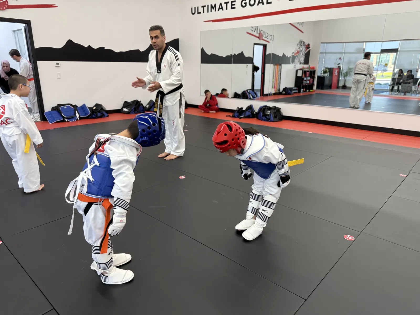 Instructor coaching young students in sparring gear