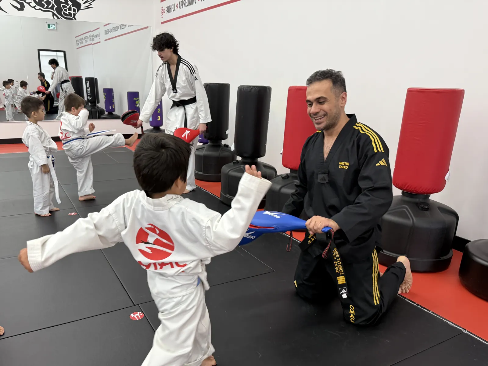 An instructor holding a kick pad for a young student